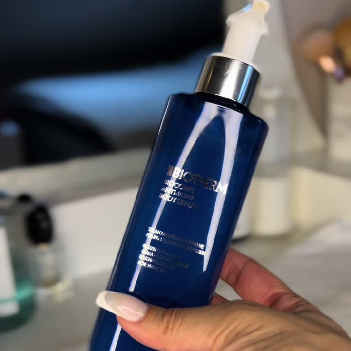 Flacon du sérum corps Biocorps de Biotherm tenu par une ambassadrice dans sa salle de bain