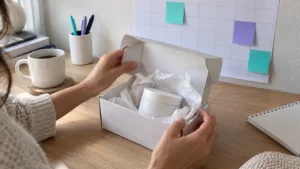 Ouverture d'une boîte de produit cosmétique devant un planning mural avec des notes turquoise et violettes