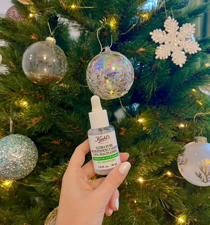 Sérum Ultra Pure au niacinamide de Kiehl’s tenu devant un sapin décoré