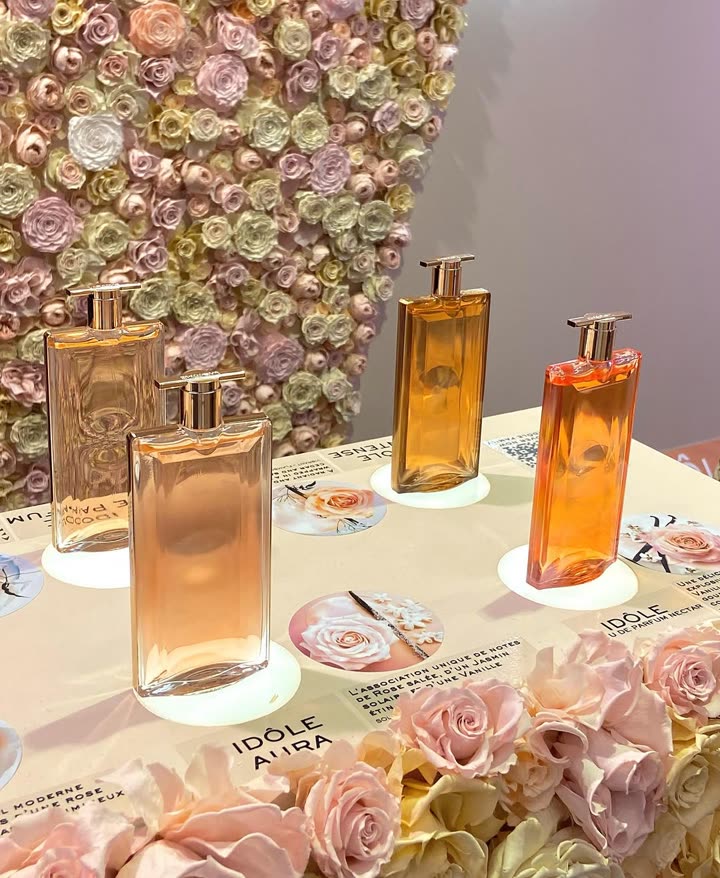Flacons de parfum Idôle exposés sur un mur de roses lors de l’événement Idôle de Lancôme